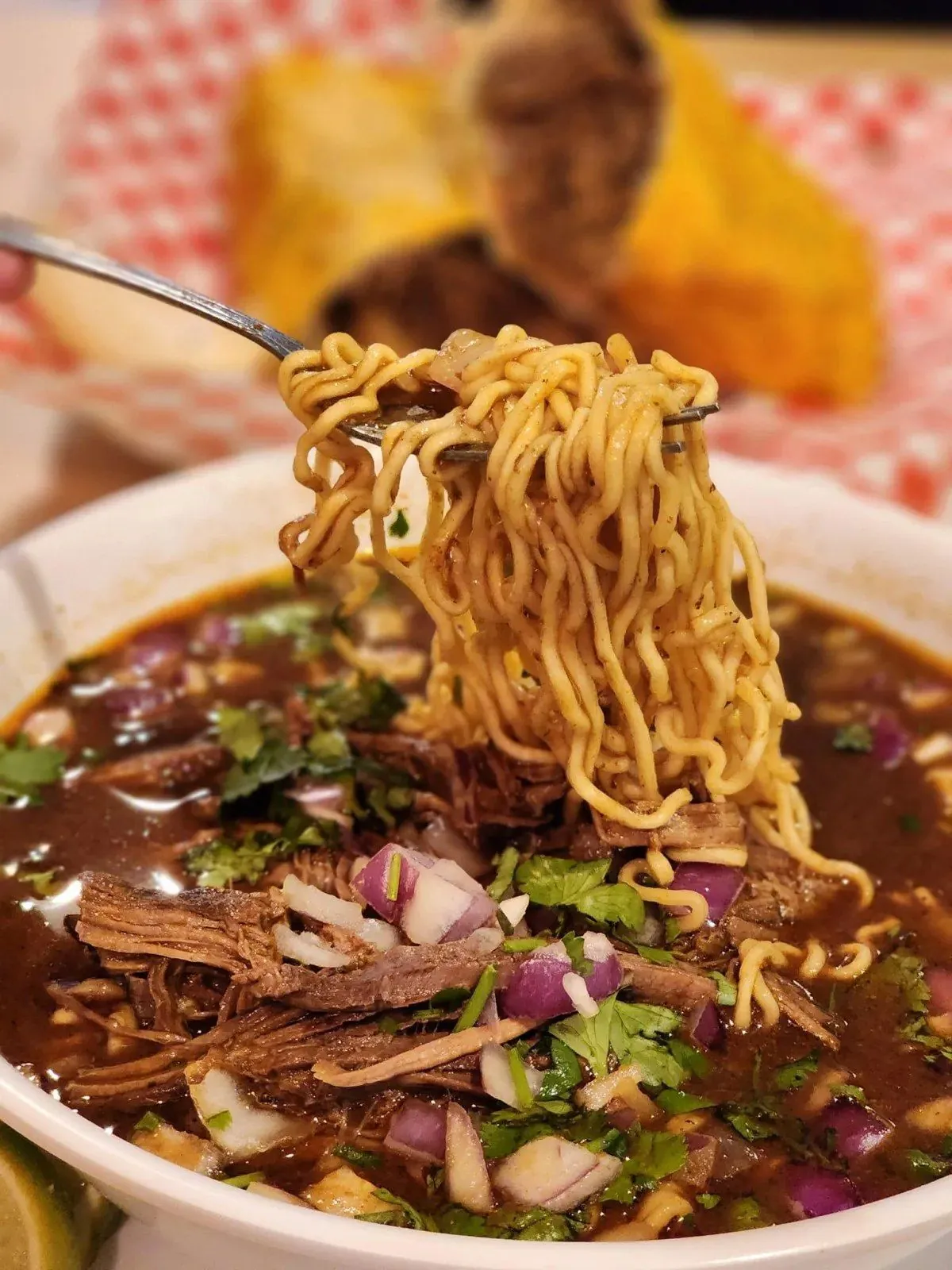Birria ramen bowl with shredded beef and fresh cilantro