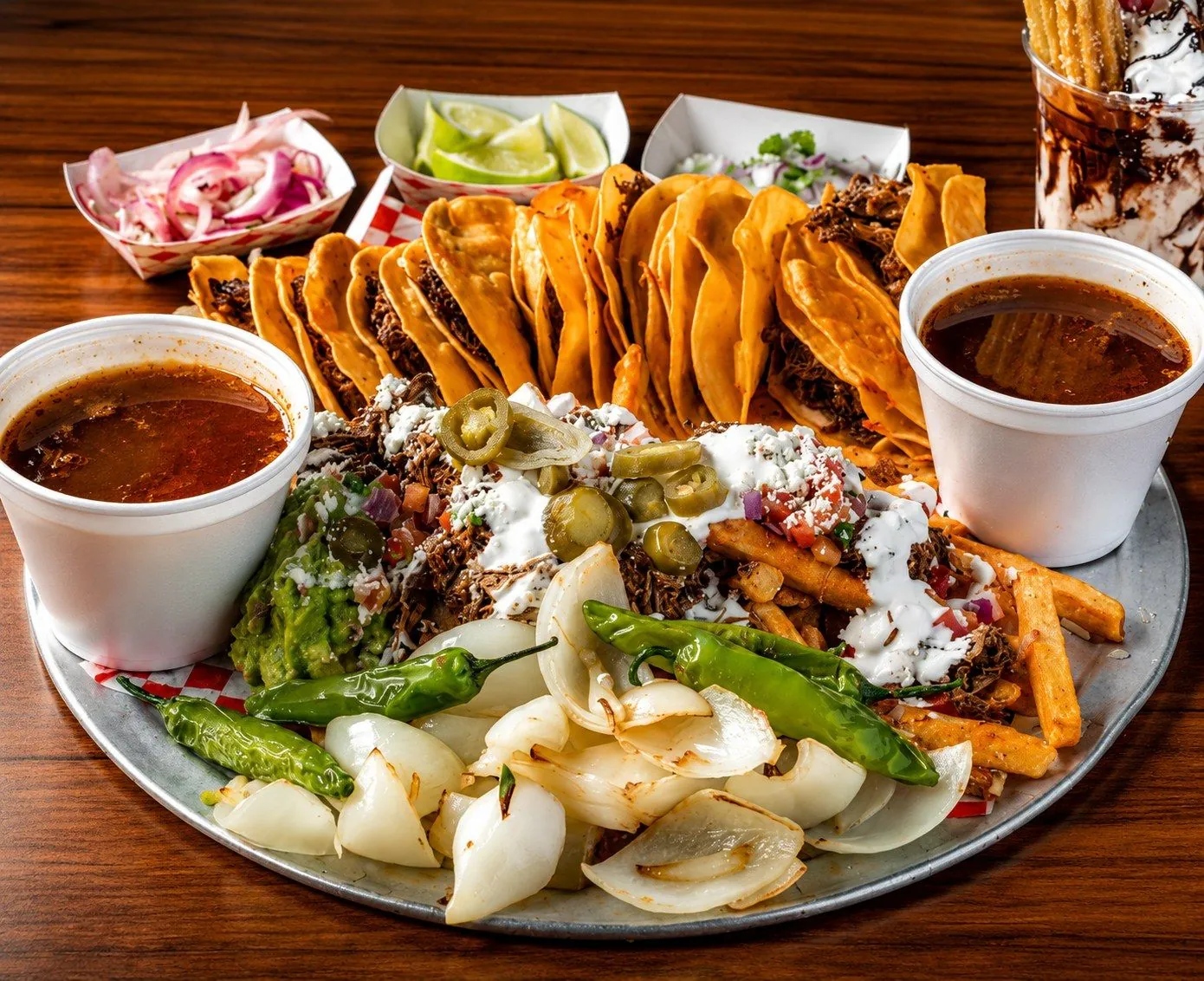 Birria tacos platter with consomé, guacamole, and grilled onions