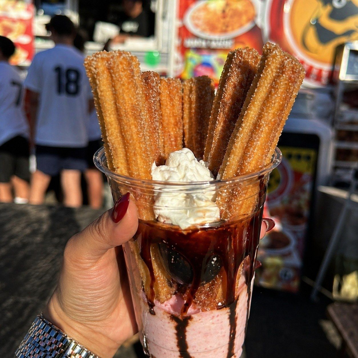 Churros in a cup with chocolate sauce and whipped cream