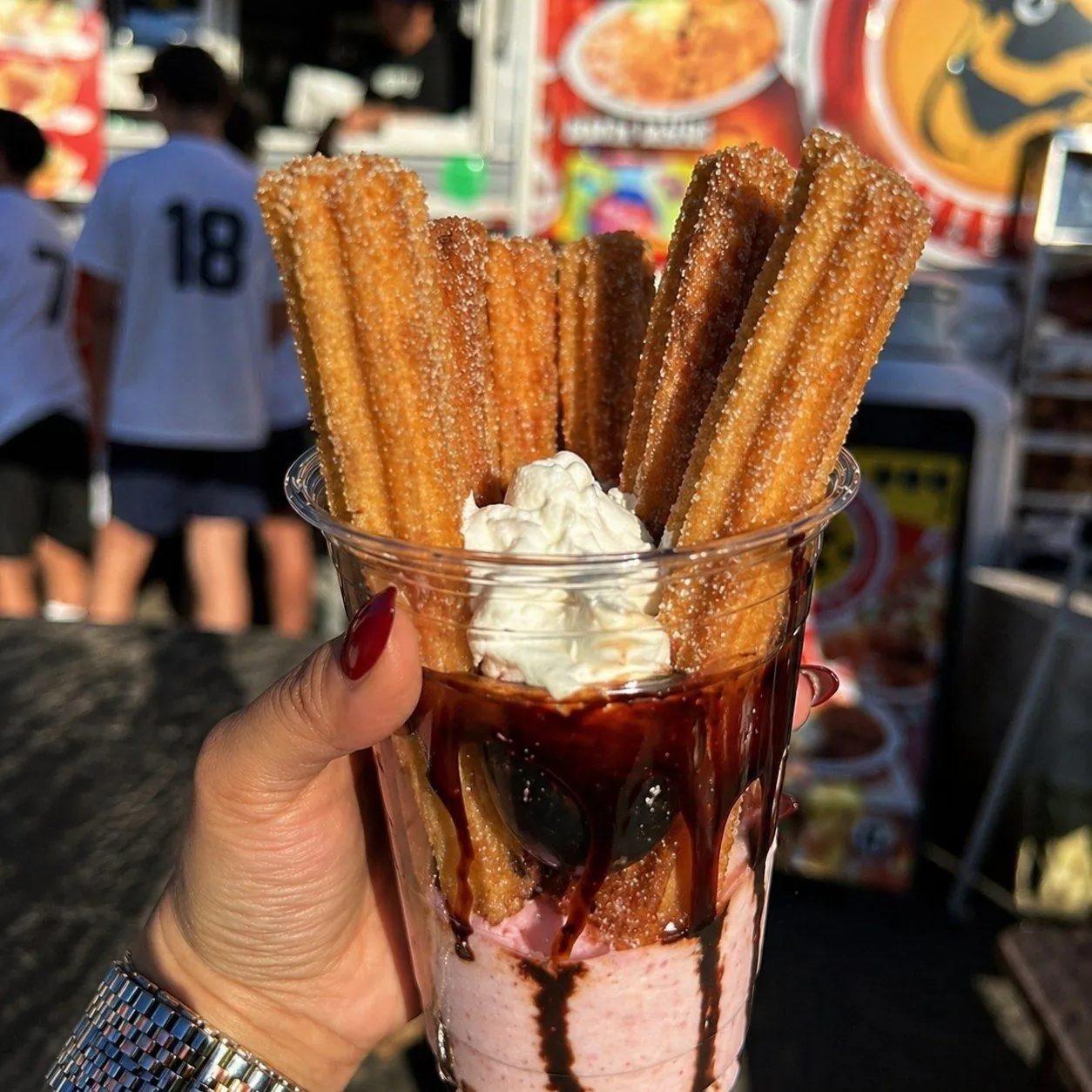 Churros in a cup with chocolate sauce and whipped cream