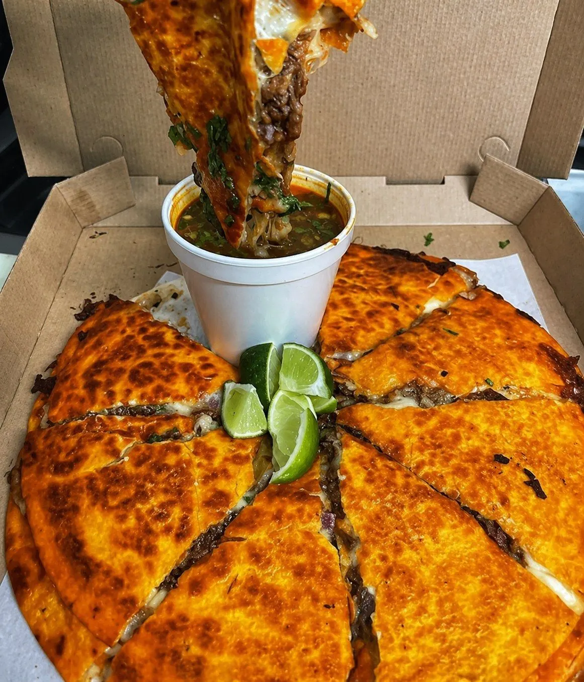 Quesabirria with a melted cheese pull, served with consomé